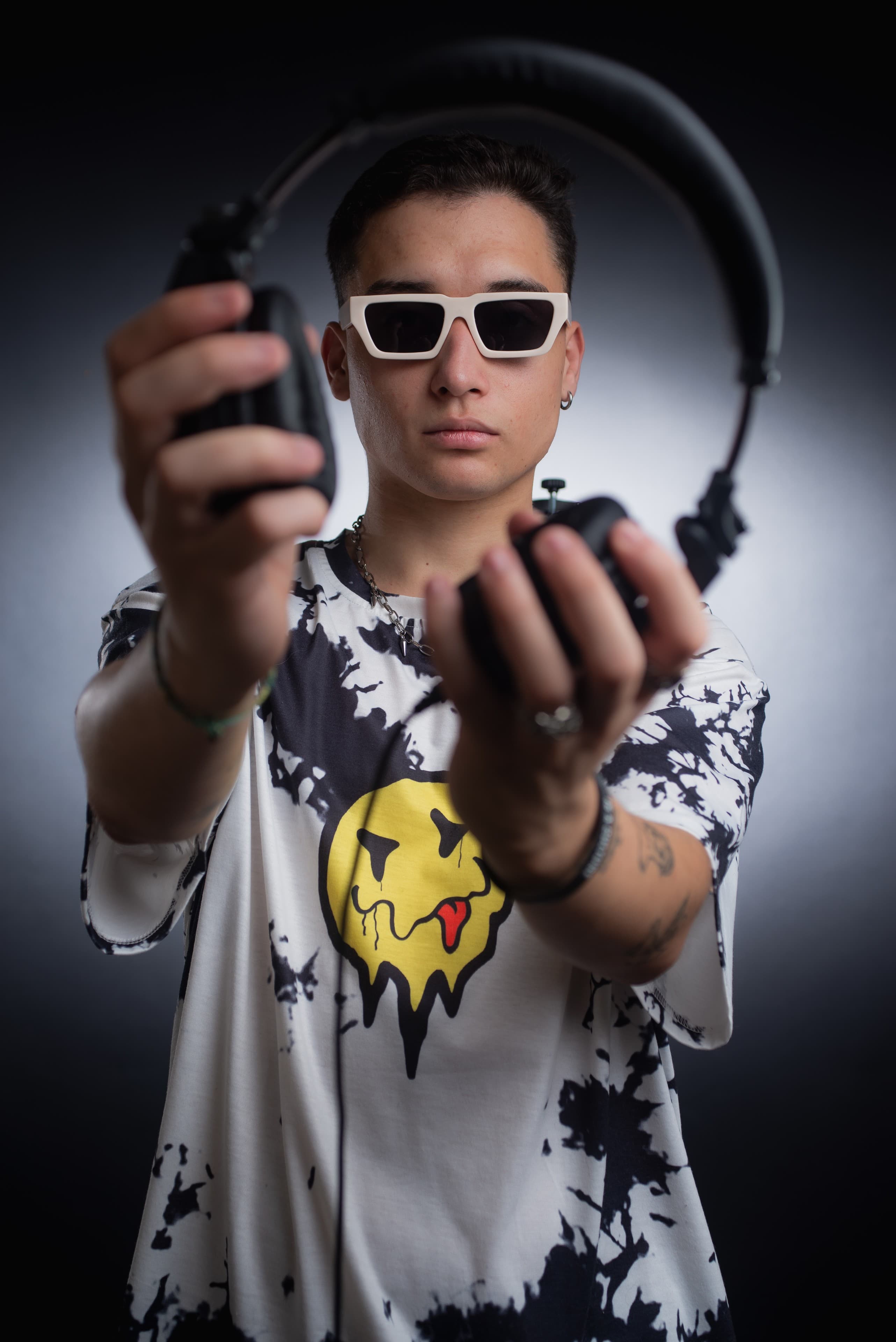 DJ Rubens segurando os fones de ouvido em direção à câmera