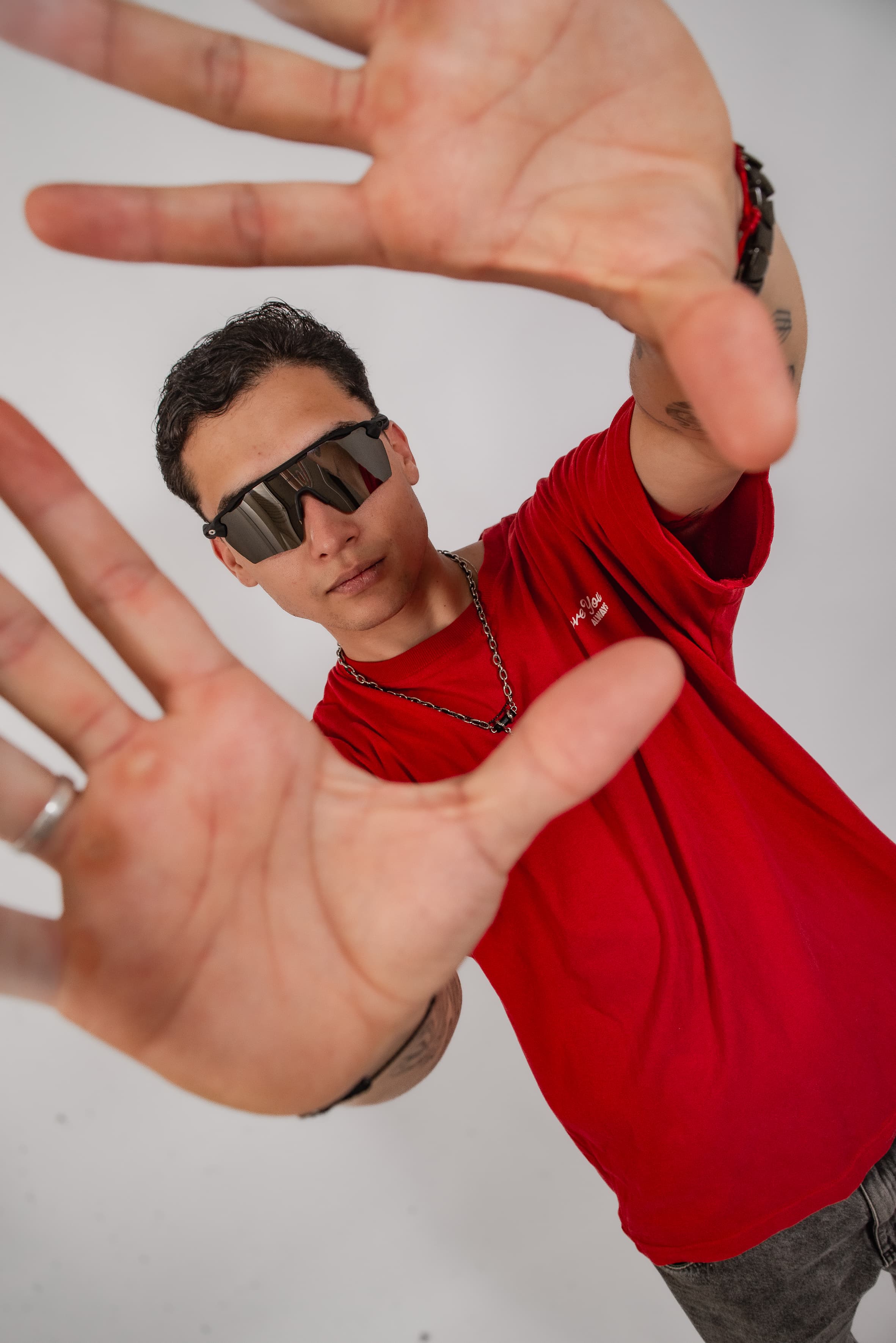 DJ Rubens de camisa vermelha enquadrando a câmera com as mãos