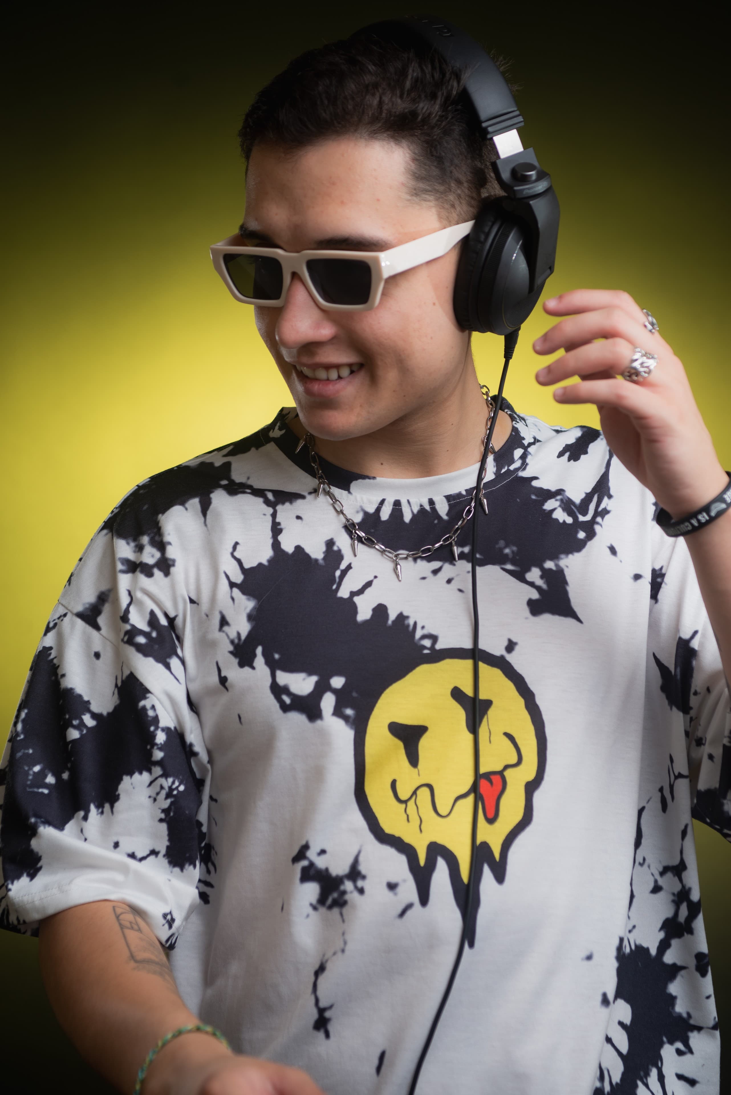 DJ Rubens sorrindo com fones de ouvido e fundo amarelo
